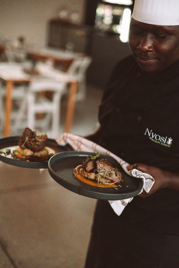 Chef at Nyosi carrying two plates of food.